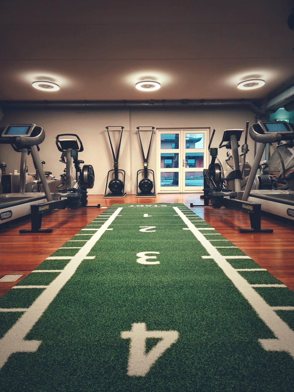 Oefenzaal van Fysiotherapiepraktijk CG met cardiotoestellen langs een sprintbaan